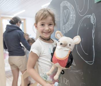 Mädchen an einer Tafel mit Plüschtier Herr Gorfion