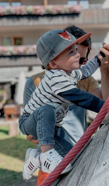 Kleinkind klettert auf dem Spielplatz des Familienhotel Gorfion Liechtenstein