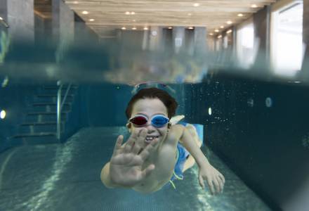 Kind winkt unter Wasser im Pool des Familienhotel Gorfion Liechtenstein