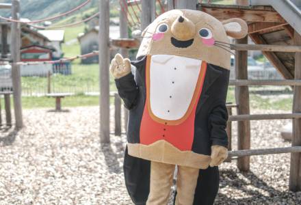 Maskottchen Herr Gorfion winkt auf dem Spielplatz