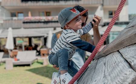 Kleinkind klettert auf dem Spielplatz des Familienhotel Gorfion Liechtenstein