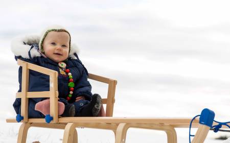 Baby sitzt auf einem Holzschlitten