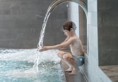 Kind am Pool-Wasserfall im Wellnessbereich des Familienhotel Gorfion Liechtenstein