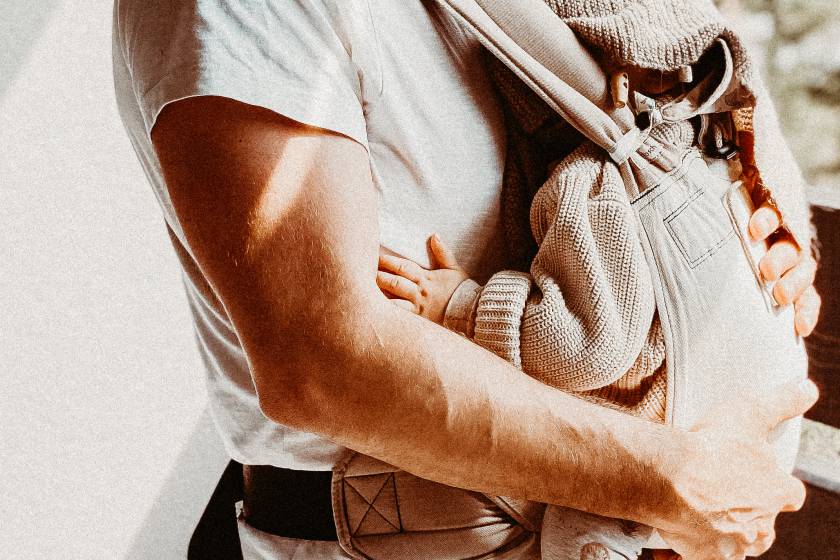 Mann hält Baby in Babytrage